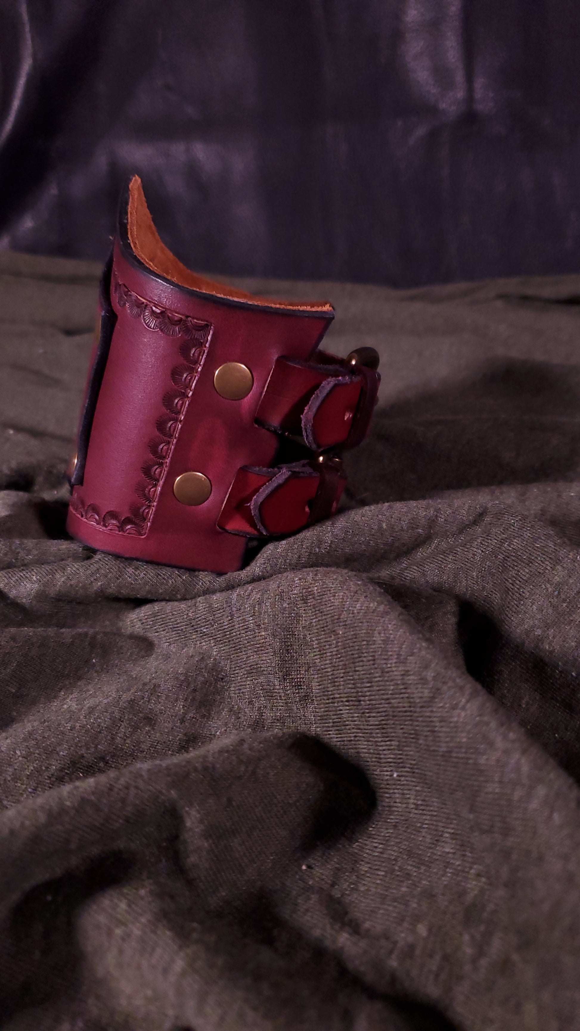 Red Cuff with a panel riveted onto it that has a mjolnir or thors hammer stamped onto it