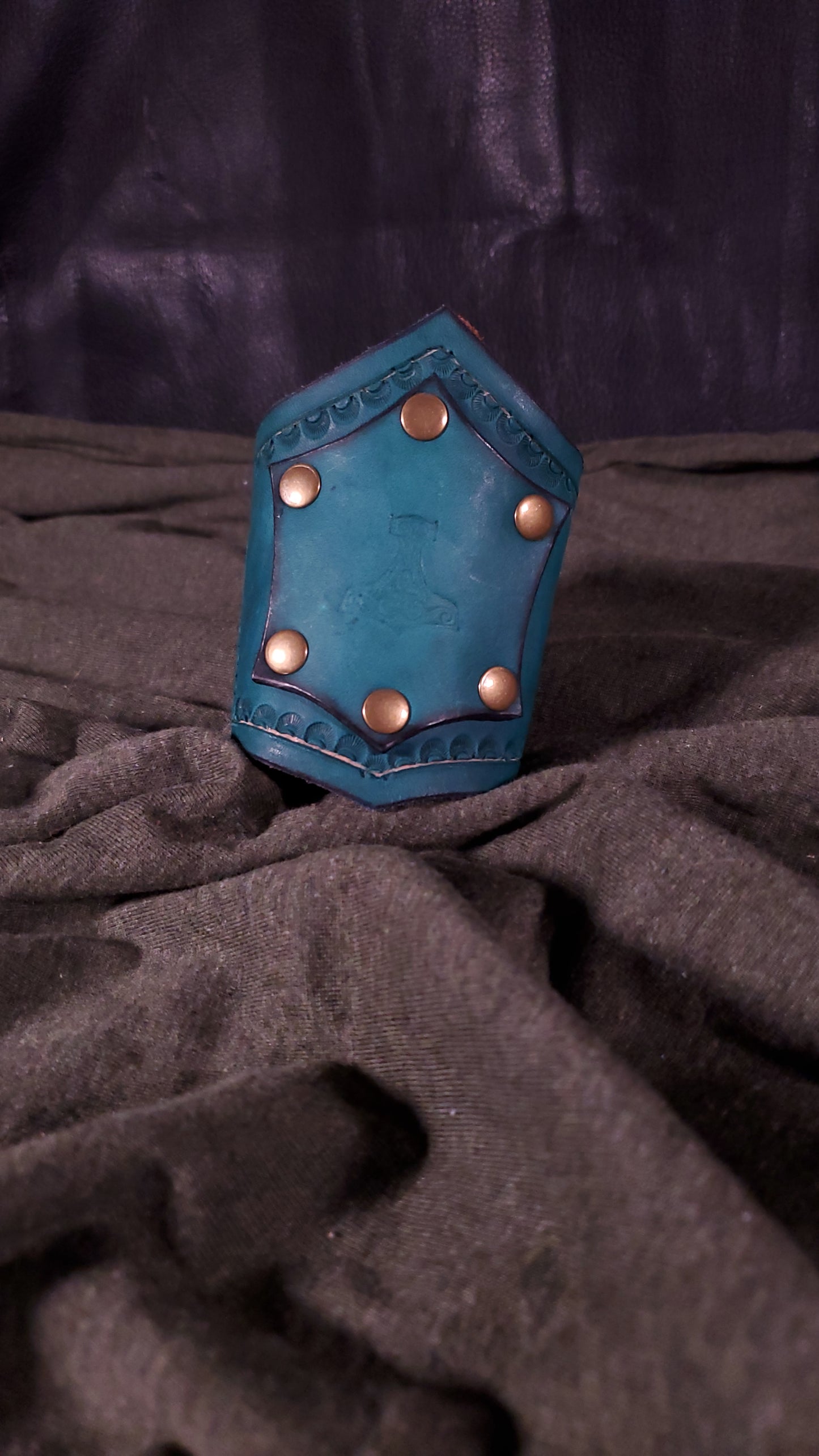 Green Cuff with a panel riveted onto it that has a mjolnir or thors hammer stamped onto it