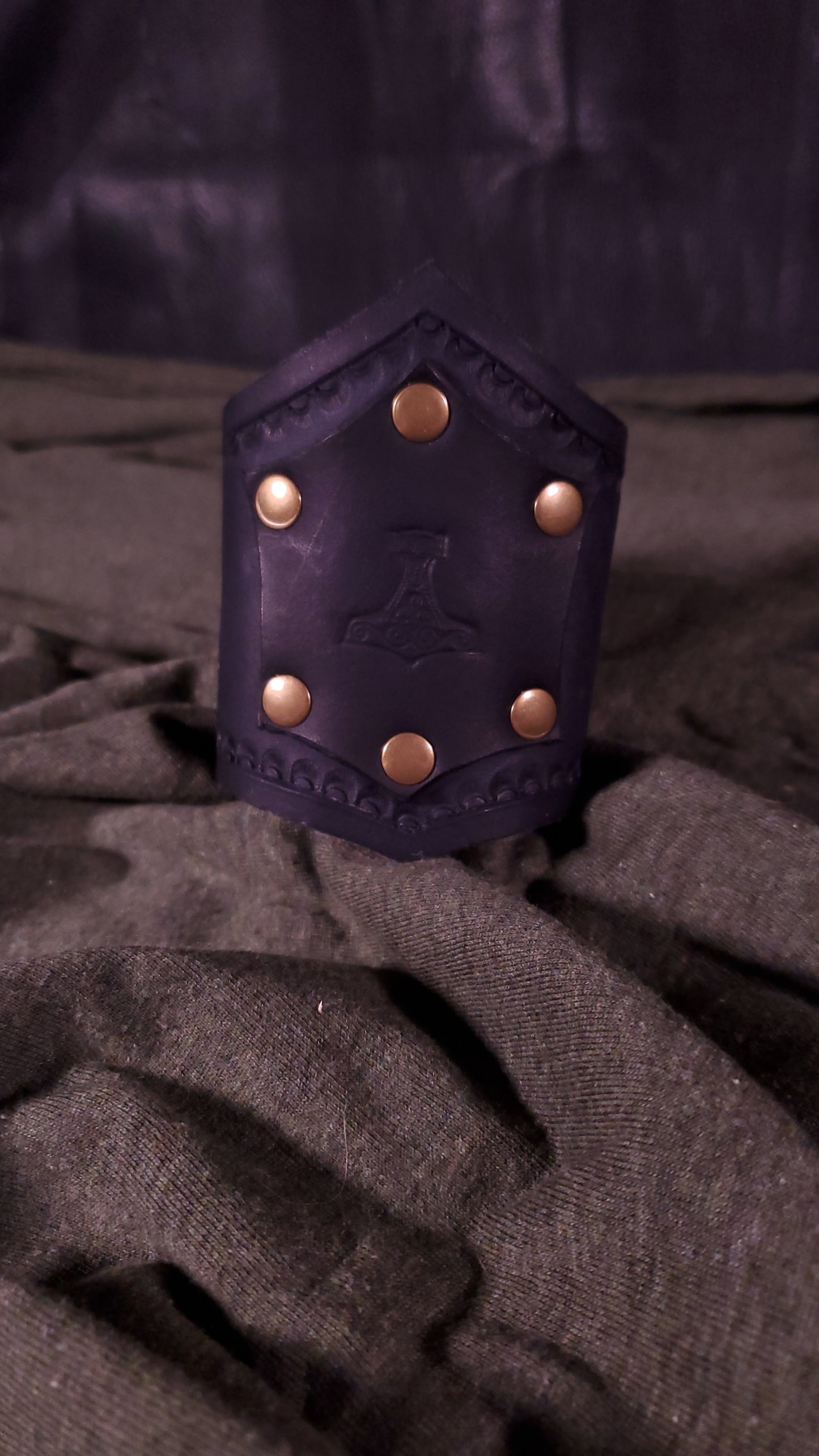 Black Cuff with a panel riveted onto it that has a mjolnir or thors hammer stamped onto it