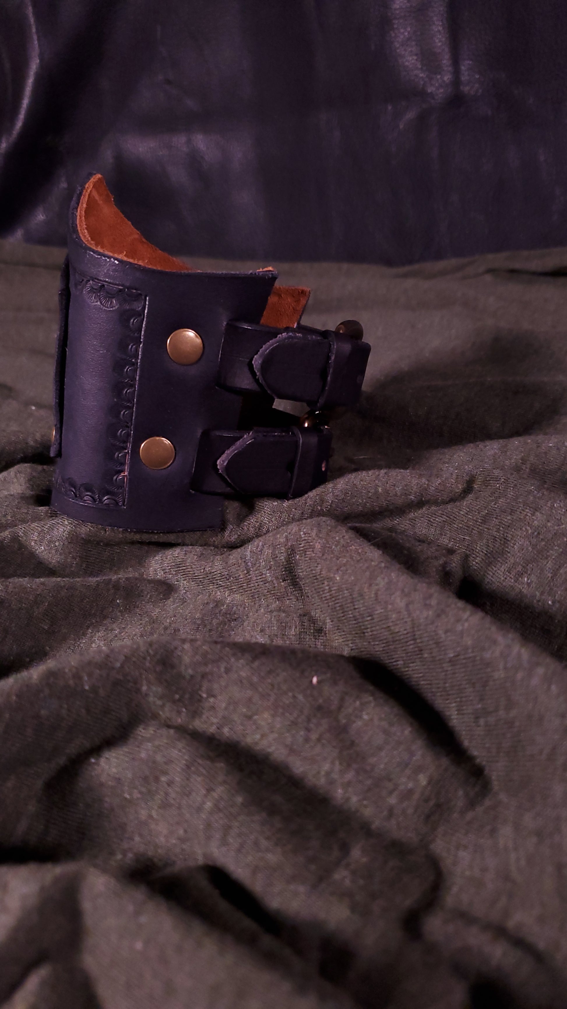 Black Cuff with a panel riveted onto it that has a mjolnir or thors hammer stamped onto it