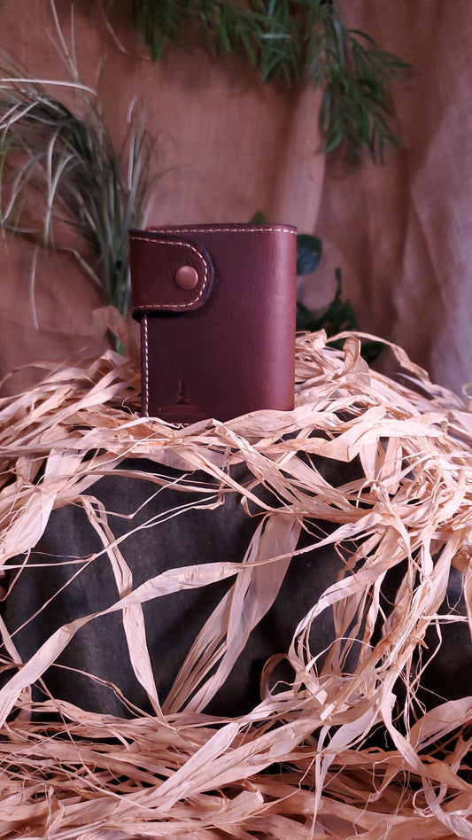 Snap closure style Bi-fold wallet in a pebbled dark brown color, featuring an antique copper snap and cream stitching.