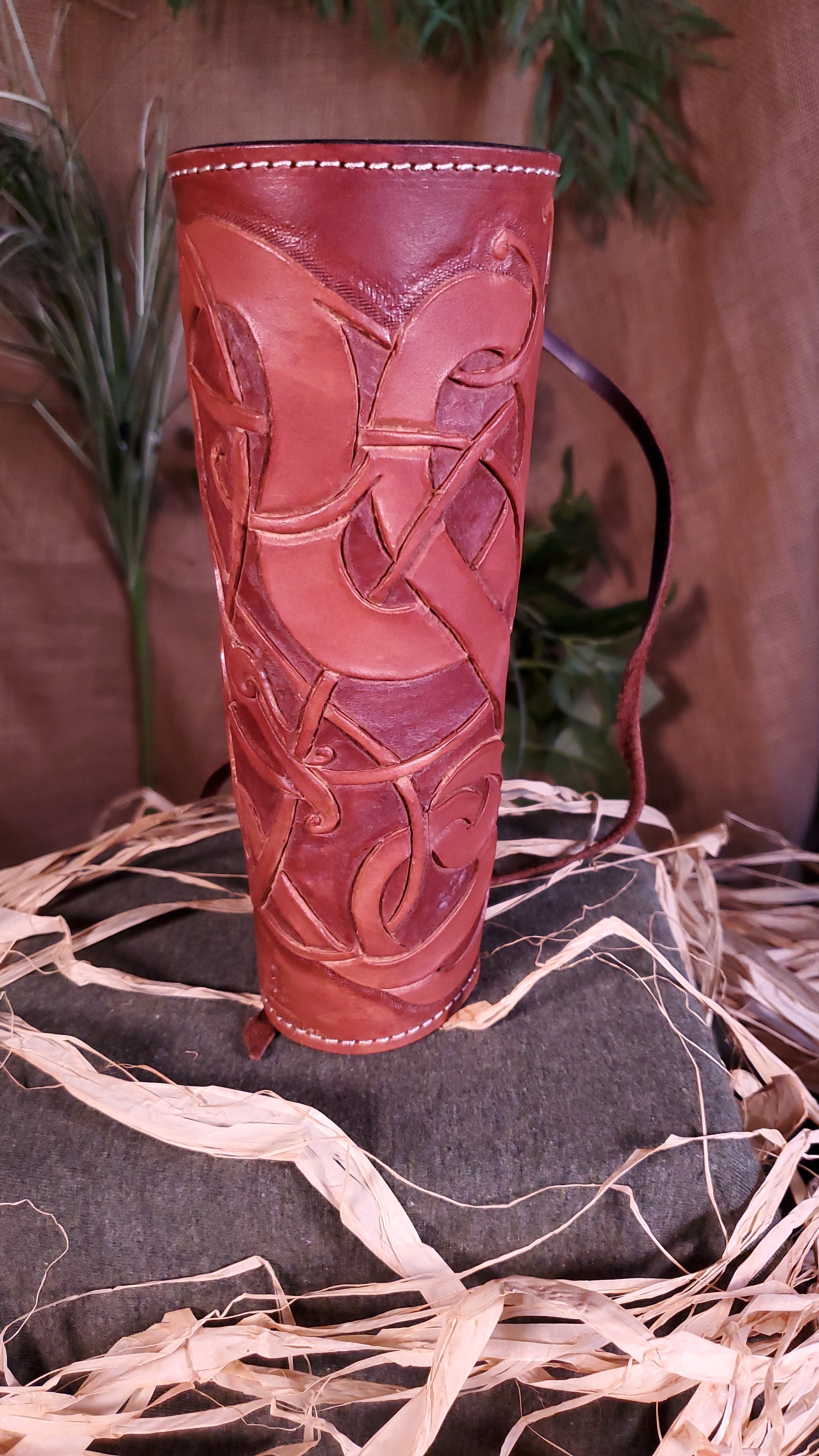 Front view of the small Bracer/arm guard. Showcasing the tooled design, as well as the mahogany color and cream colored stitching.