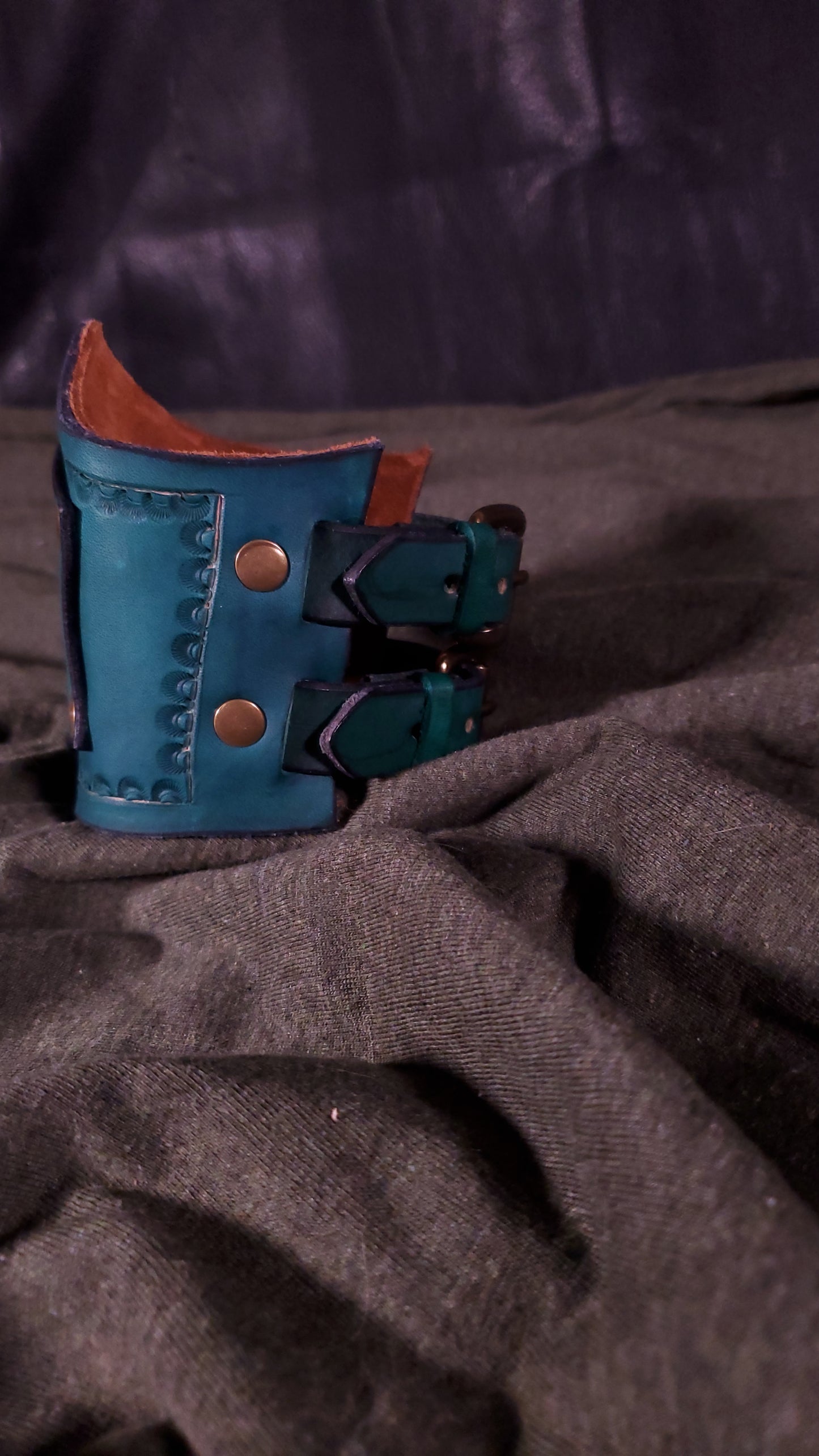 Green Cuff with a panel riveted onto it that has a mjolnir or thors hammer stamped onto it