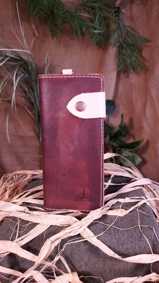 Exterior picture of a dark brown biker wallet with a natural, almost white snap strap and d-ring strap. Cream stitching, nickel d-ring, antique copper snap